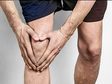 Image of man holding his knee in the shape of a heart.