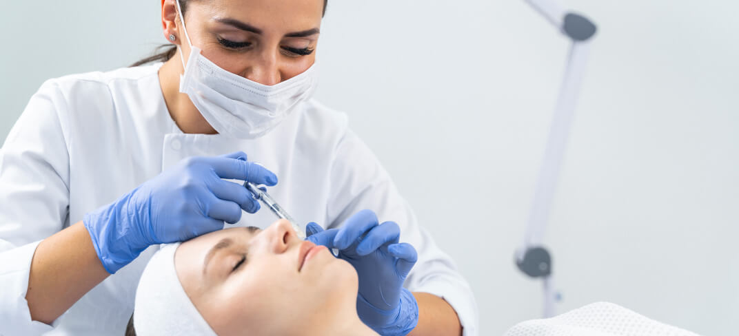 Plastic surgeon administering injections to patient's skin