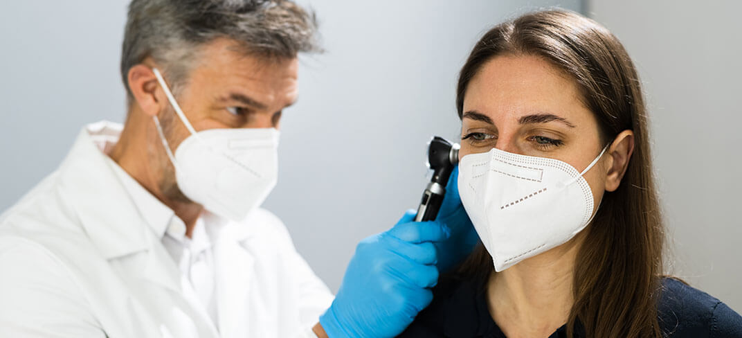 Doctor using an otoscope to look in a woman's ear