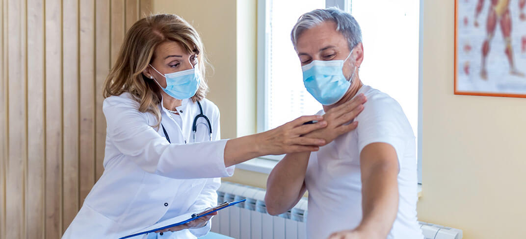 Man showing woman doctor where his shoulder hurts